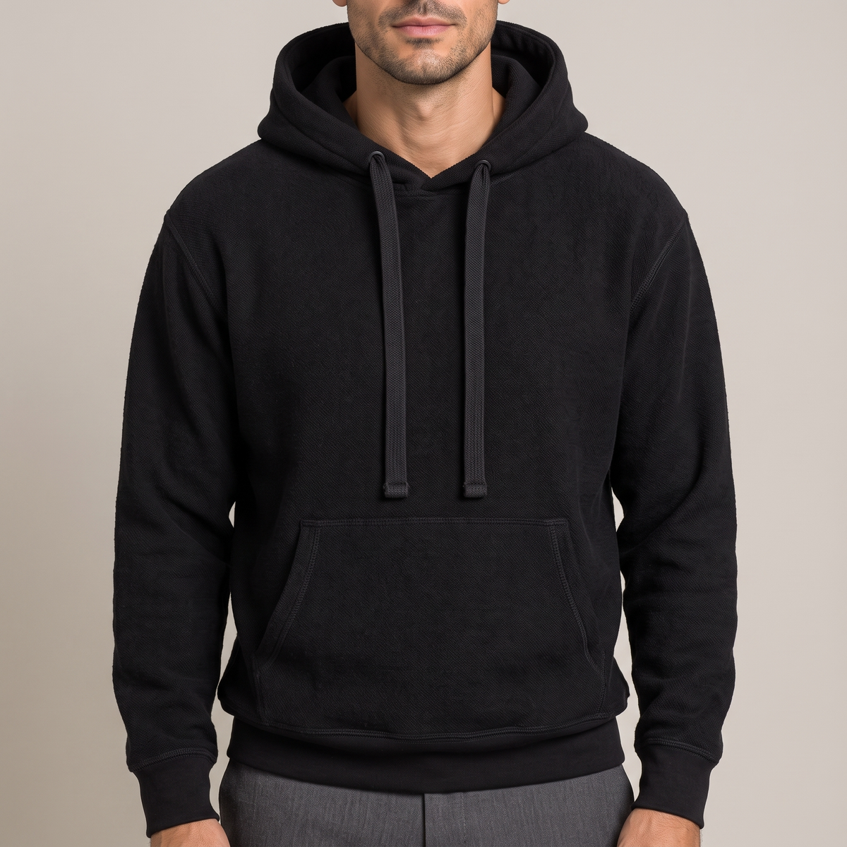 Close detail of the hood, drawcords and kangaroo pocket on the cotton terry hoodie, in black